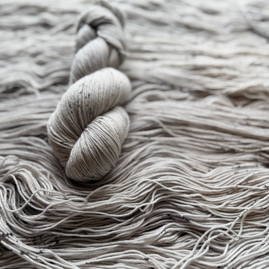 Close-up of a skein of gray yarn on a textured surface