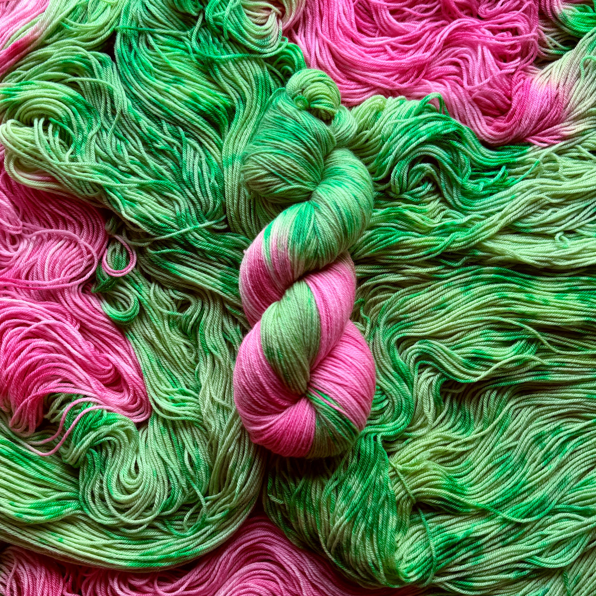 Skein of Pink Tulips hand-dyed assigned pooling sock yarn in variegated green with tulip pink contrast colour by Auridon Yarns