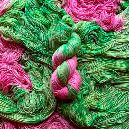 Skein of Pink Tulips hand-dyed assigned pooling sock yarn in variegated green with tulip pink contrast colour by Auridon Yarns