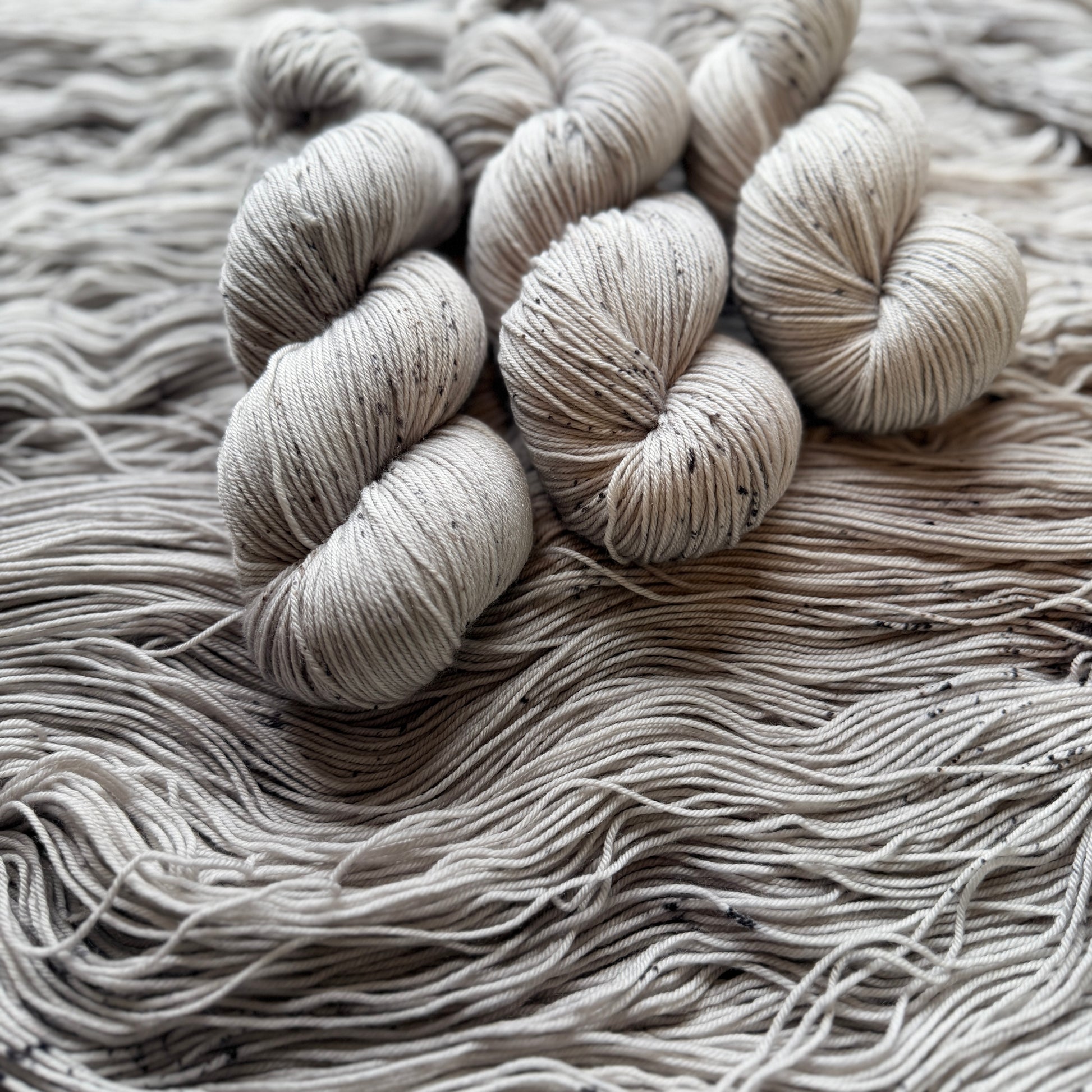 Three skeins of gray yarn on a textured surface