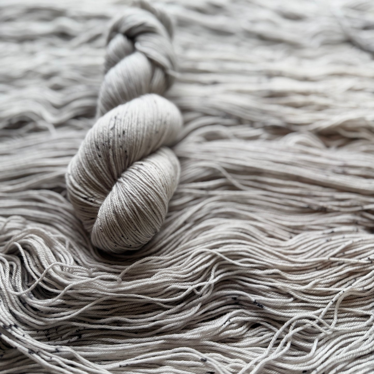 Close-up of a skein of gray yarn on a textured surface