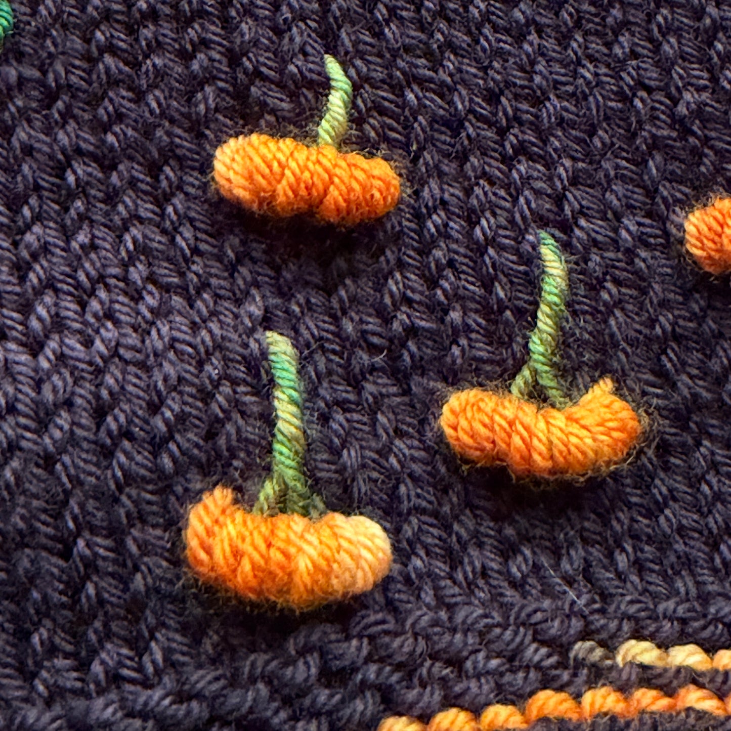 Pumpkin Patch Noir assigned pooling yarn, detail view of the pumpkin motif on black